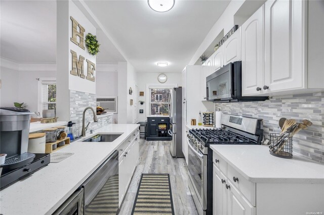 kitchen with sink, tasteful backsplash, white cabinetry, ornamental molding, and stainless steel appliances