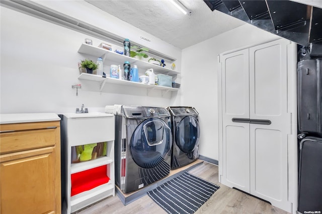 laundry area featuring separate washer and dryer, a textured ceiling, and light wood-type flooring