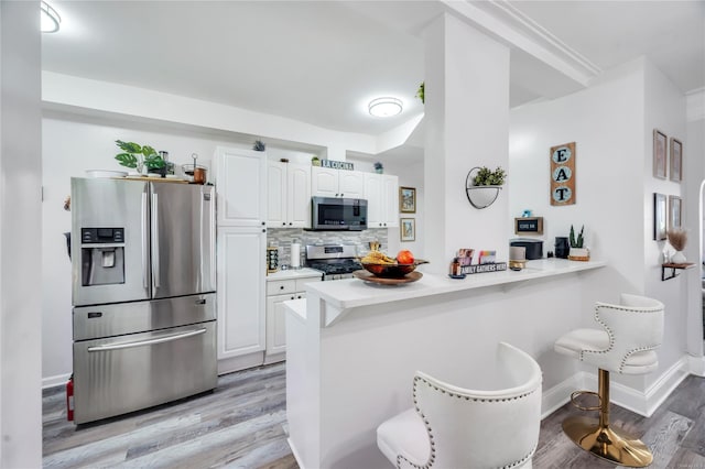 kitchen featuring white cabinetry, tasteful backsplash, stainless steel appliances, and kitchen peninsula