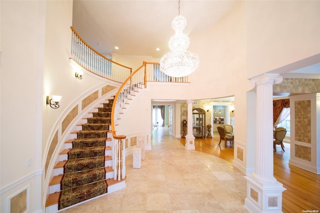 foyer featuring a wealth of natural light, light wood-type flooring, ornate columns, and a towering ceiling