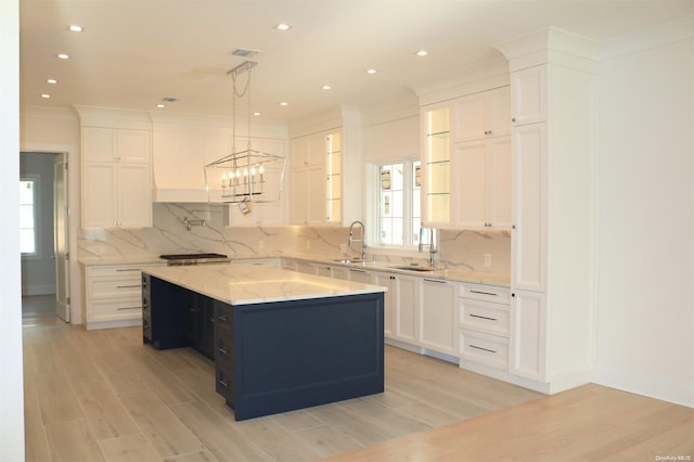 kitchen featuring a center island, light hardwood / wood-style flooring, backsplash, decorative light fixtures, and white cabinets