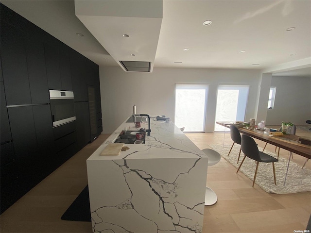 kitchen featuring oven and an island with sink