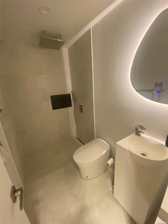 bathroom with tiled shower, vanity, and toilet