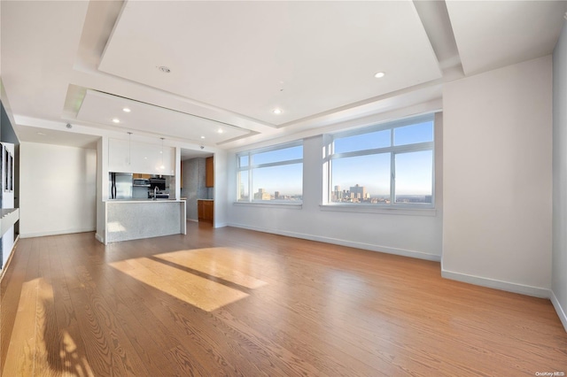 unfurnished living room featuring light wood-type flooring and sink