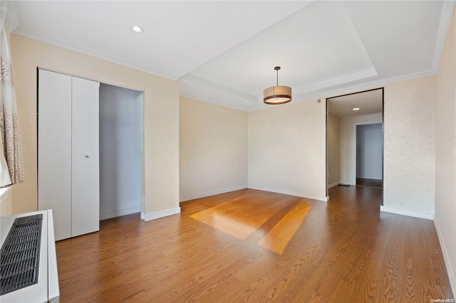 interior space with hardwood / wood-style flooring, a raised ceiling, and ornamental molding