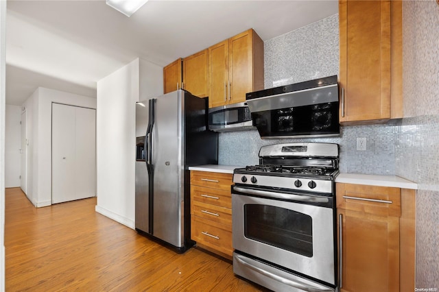 kitchen with appliances with stainless steel finishes, light wood-type flooring, and tasteful backsplash