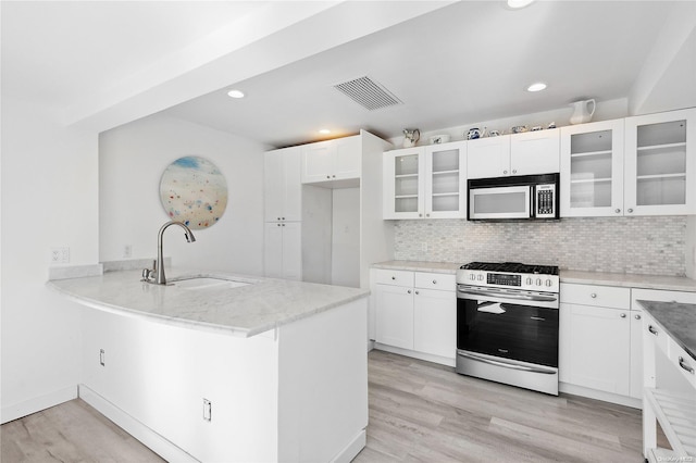 kitchen with white cabinets, sink, light wood-type flooring, kitchen peninsula, and stainless steel appliances