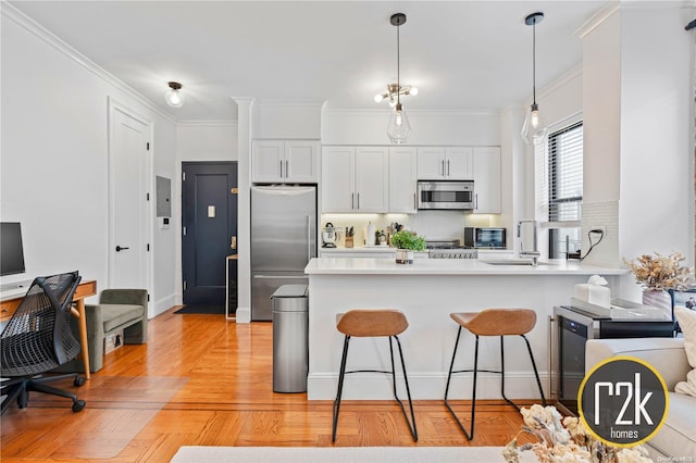 kitchen featuring white cabinets, sink, ornamental molding, kitchen peninsula, and stainless steel appliances