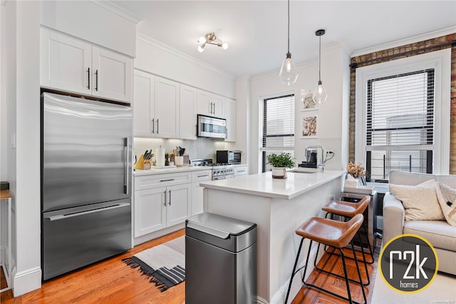 kitchen featuring white cabinetry, crown molding, a breakfast bar area, decorative backsplash, and appliances with stainless steel finishes