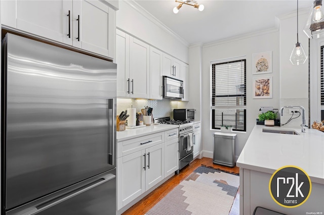 kitchen with white cabinetry, sink, light hardwood / wood-style flooring, backsplash, and high end appliances