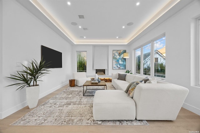 living room with a tray ceiling and light hardwood / wood-style flooring