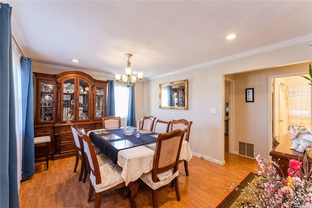 dining space with wood-type flooring, crown molding, and a notable chandelier