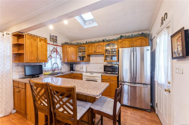 kitchen with a skylight, sink, stainless steel appliances, kitchen peninsula, and a breakfast bar