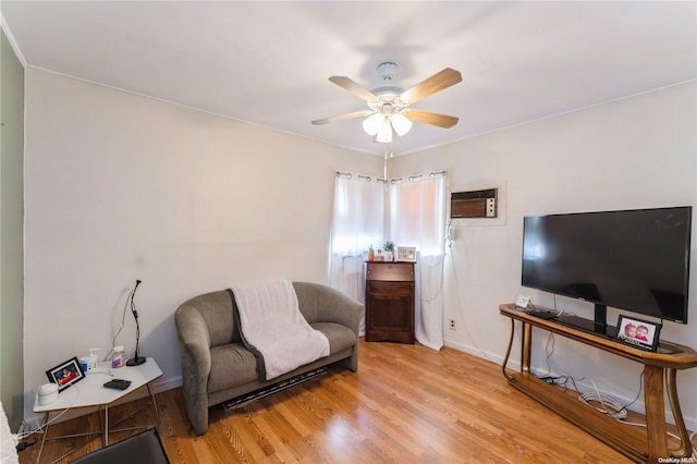 sitting room with a wall unit AC, ceiling fan, and light wood-type flooring