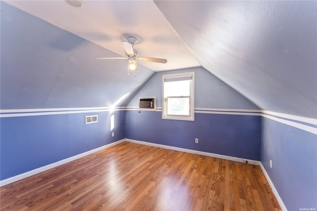 additional living space featuring hardwood / wood-style flooring, vaulted ceiling, ceiling fan, and a wall unit AC