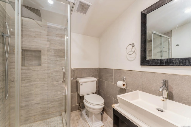 bathroom with vanity, an enclosed shower, tile walls, and toilet