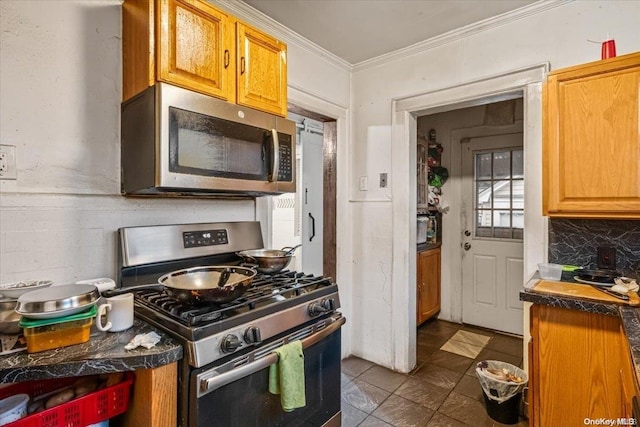 kitchen featuring decorative backsplash, tile patterned flooring, stainless steel appliances, and ornamental molding