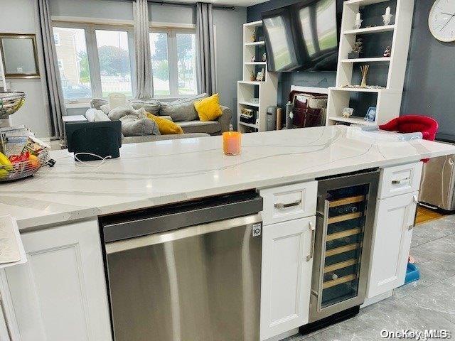 kitchen with dishwasher, white cabinets, wine cooler, and light stone counters