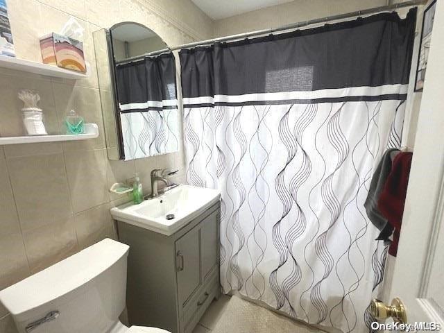 bathroom featuring vanity, tile walls, and walk in shower