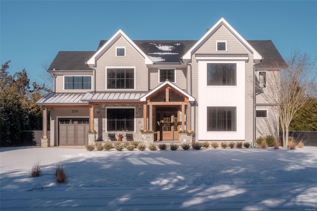 view of front of property featuring a garage, metal roof, a standing seam roof, and driveway