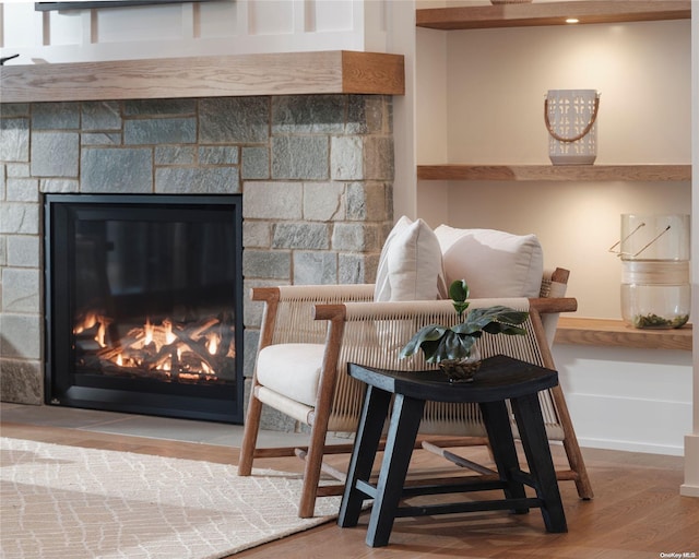 interior space with a stone fireplace and wood finished floors