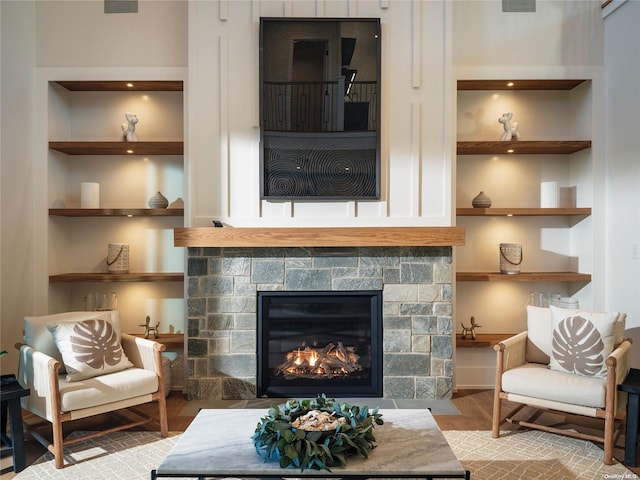 living room with visible vents, built in shelves, wood finished floors, and a fireplace