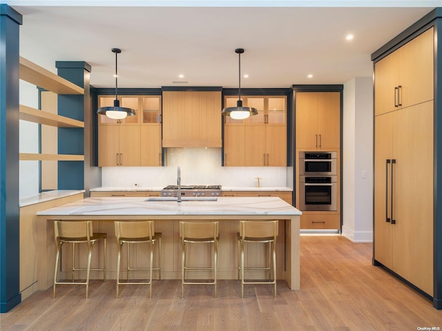 kitchen featuring light wood-type flooring, pendant lighting, stainless steel appliances, a breakfast bar area, and decorative backsplash