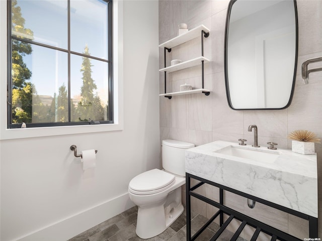 half bath with tile walls, toilet, tasteful backsplash, and a sink