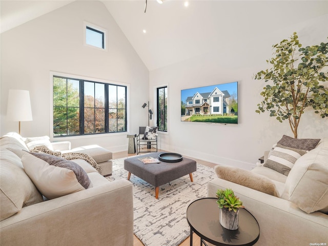 living room with high vaulted ceiling, baseboards, and wood finished floors