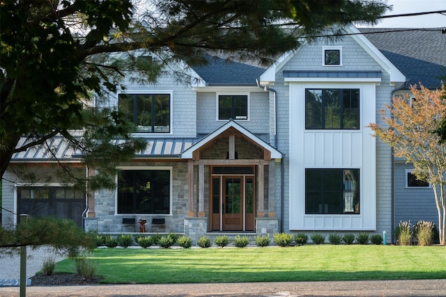 view of front of house with stone siding, a front lawn, a standing seam roof, and metal roof