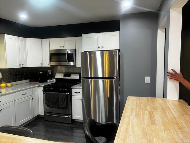 kitchen featuring tasteful backsplash, white cabinetry, dark hardwood / wood-style flooring, and appliances with stainless steel finishes