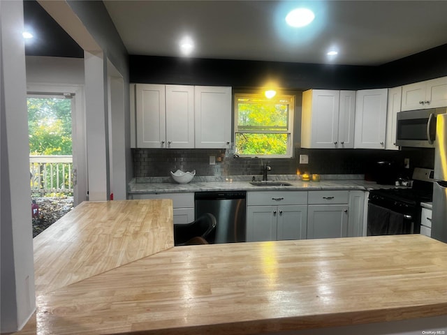 kitchen with white cabinetry, sink, wood counters, decorative backsplash, and appliances with stainless steel finishes