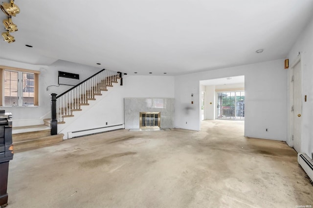 unfurnished living room with concrete flooring, a wealth of natural light, baseboard heating, and a premium fireplace