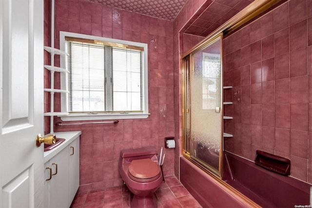 full bathroom with tile patterned floors, toilet, shower / bath combination with glass door, and tile walls