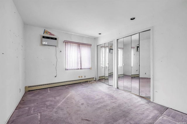 unfurnished bedroom with an AC wall unit, light colored carpet, two closets, and a baseboard heating unit