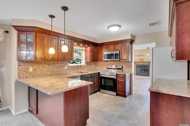 kitchen with sink, backsplash, kitchen peninsula, decorative light fixtures, and appliances with stainless steel finishes