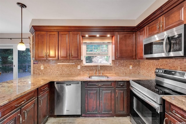 kitchen featuring light stone countertops, appliances with stainless steel finishes, decorative backsplash, sink, and hanging light fixtures