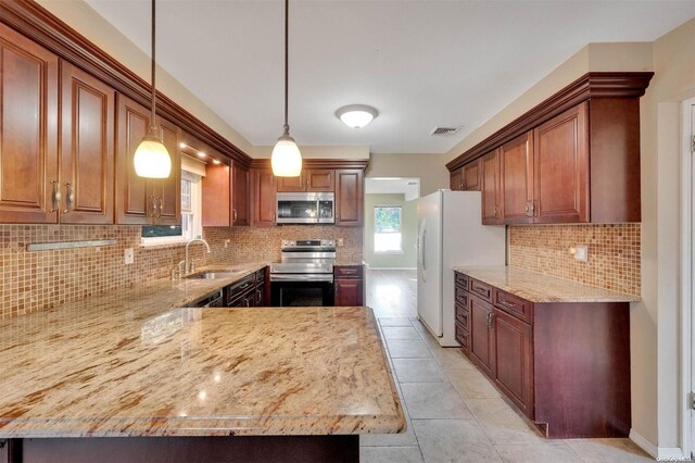 kitchen featuring kitchen peninsula, sink, pendant lighting, and appliances with stainless steel finishes