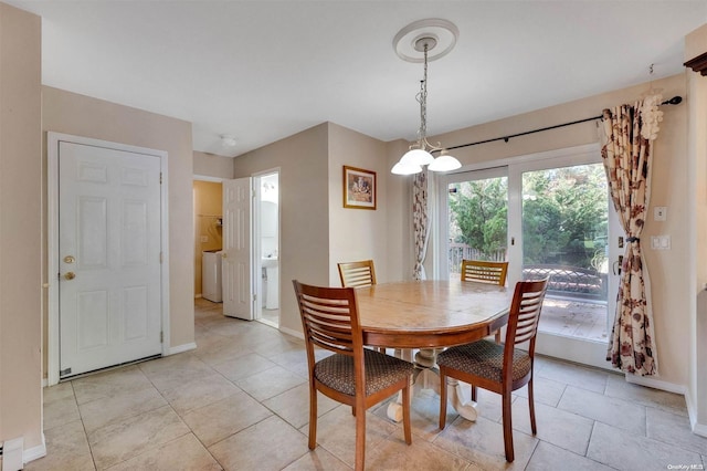 dining room featuring washer / dryer, light tile patterned floors, a baseboard radiator, and an inviting chandelier