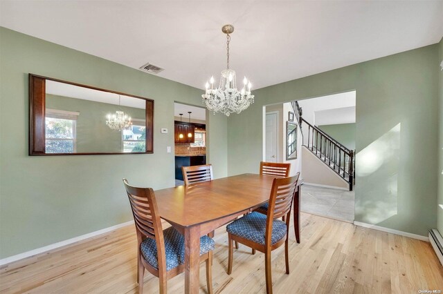 dining room with a chandelier, light hardwood / wood-style floors, and a baseboard radiator