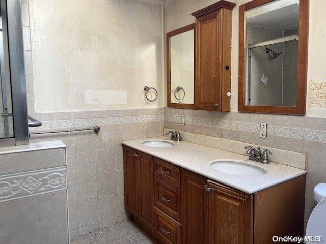 bathroom with tile patterned floors, vanity, tile walls, and toilet