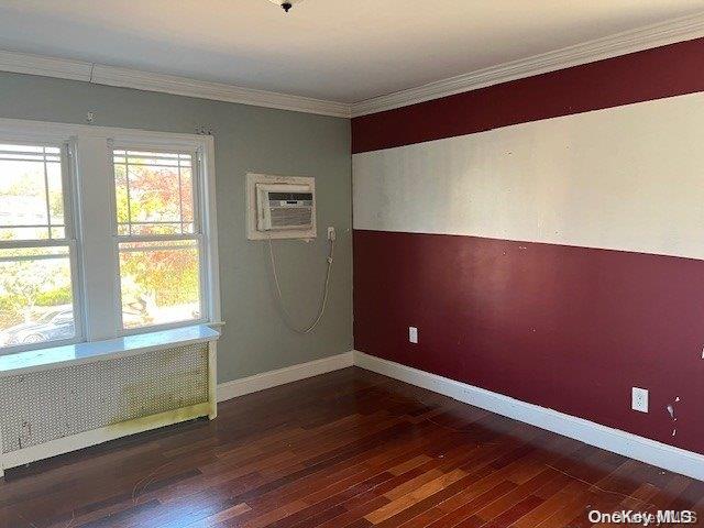 unfurnished room with a wall mounted air conditioner, dark hardwood / wood-style flooring, crown molding, and radiator