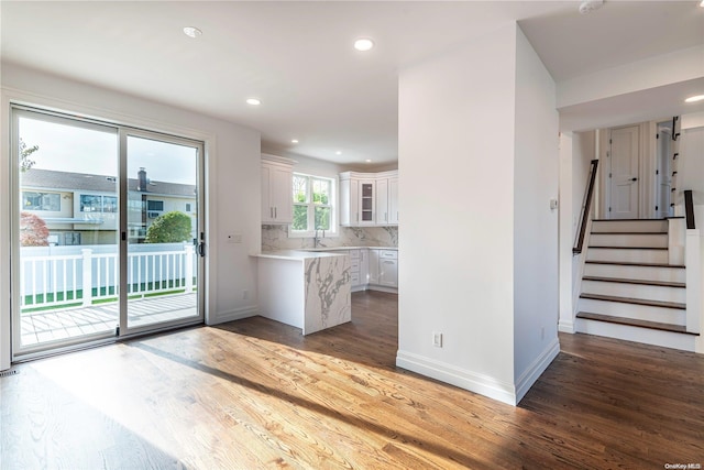 kitchen with tasteful backsplash, white cabinetry, hardwood / wood-style floors, and sink