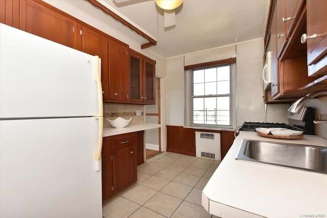 kitchen featuring light tile patterned flooring, radiator, sink, ceiling fan, and white fridge