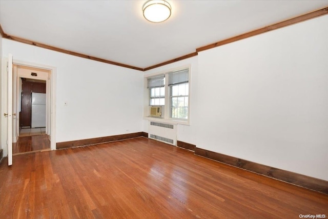 empty room with radiator heating unit, ornamental molding, and hardwood / wood-style flooring