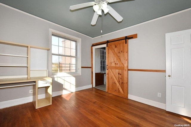 unfurnished bedroom featuring a barn door, ceiling fan, and wood-type flooring