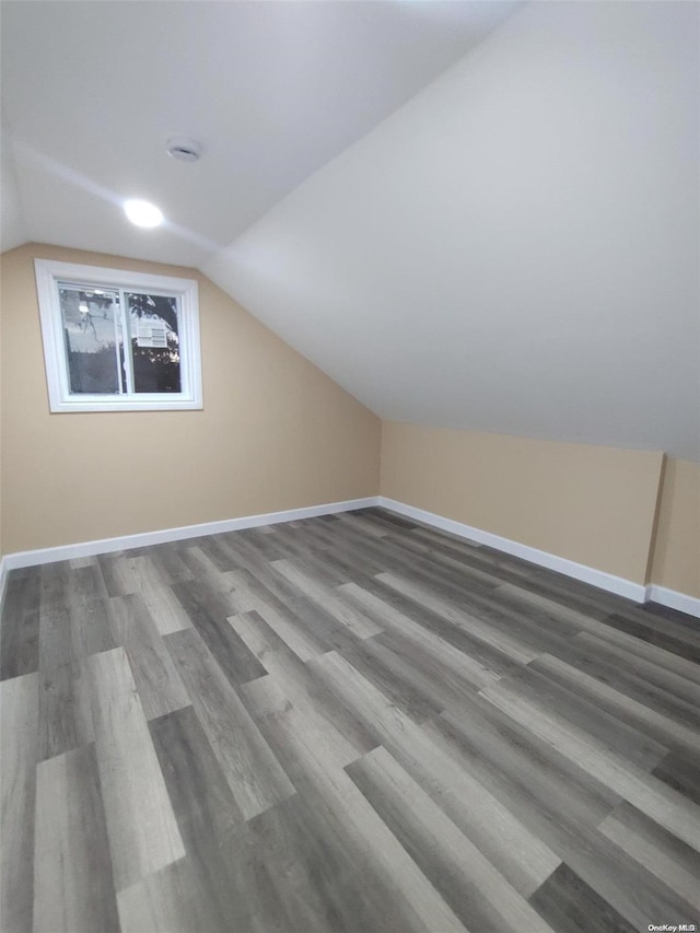 additional living space with hardwood / wood-style floors and vaulted ceiling