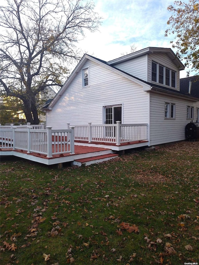 back of property with a yard and a wooden deck