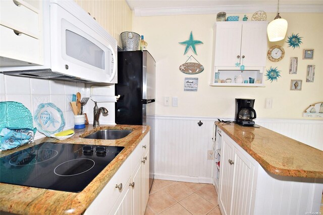 50 Rampasture Rd Unit 6, Hampton Bays, NY 11946 - kitchen with black electric stovetop, white microwave, a wainscoted wall, a sink, and white cabinetry