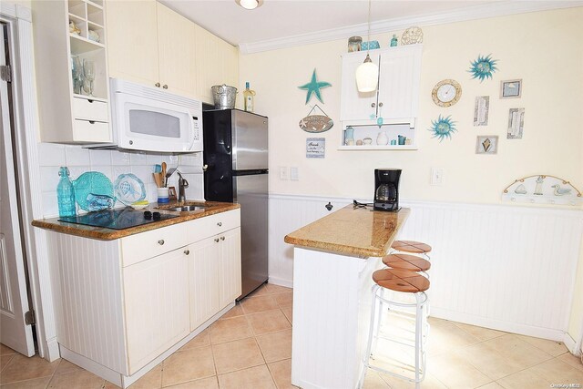 50 Rampasture Rd Unit 6, Hampton Bays, NY 11946 - kitchen featuring white microwave, black electric stovetop, freestanding refrigerator, a peninsula, and a wainscoted wall